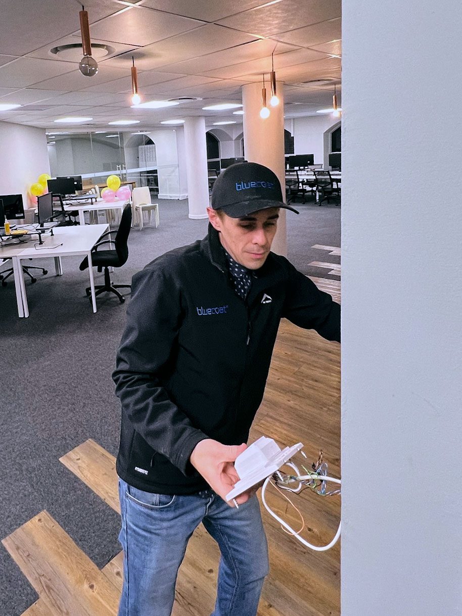 A bluecoat IT technician installing wireless equipment in an office