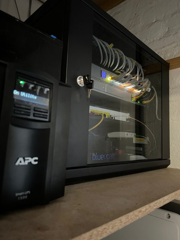 A tidy wall-mounted network cabinet with labelled patching and backup power