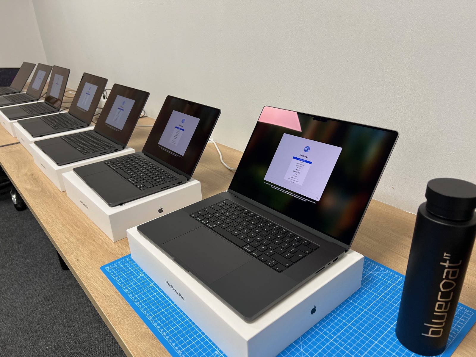 A row of new laptops on a bench running through first-time setup