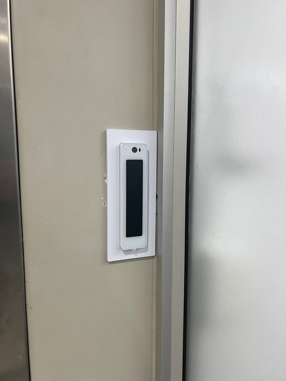 A UniFi Access card reader mounted beside a glass office door